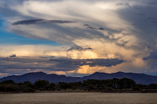 Dramatic clouds over mountains and field