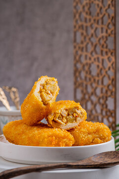 A delicious Indonesian snack called Risol and Risoles filled with chopped vegetables, chicken pieces mayonnaise and fried bread crumbs, served on a white plate on a stone texstured table