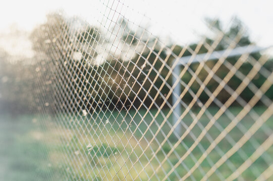 Close-up of a soccer goal net against a sunny,  defocused summer background
