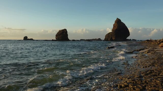 Majestic rock formations at Papuma Beach with sea waves washing the shore on a sunny morning, Jember landscape, East Java.