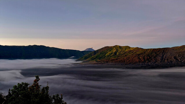 Soft sunrise colors illuminating the sea of clouds around Mount Bromo in East Java, Indonesia.