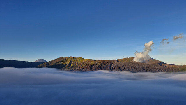 Mountain ridges surrounding the Bromo caldera emerging above a blanket of clouds in East Java, Indonesia.