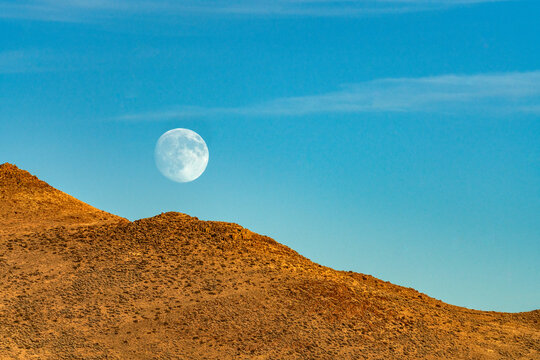 Moon rising over rocky hillside