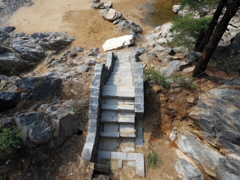 Stone steps descend through rocky terrain toward a sandy shore and calm water