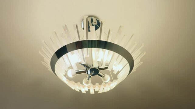Modern ceiling lamp light fixture glowing on ceiling in newly renovated residential apartment room.