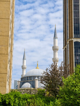 View of a mosque framed by buildings against a blue sky during the day in an urban area