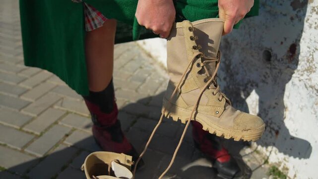 Boots combat putting on woman changing from red footwear to beige military shoes on the street