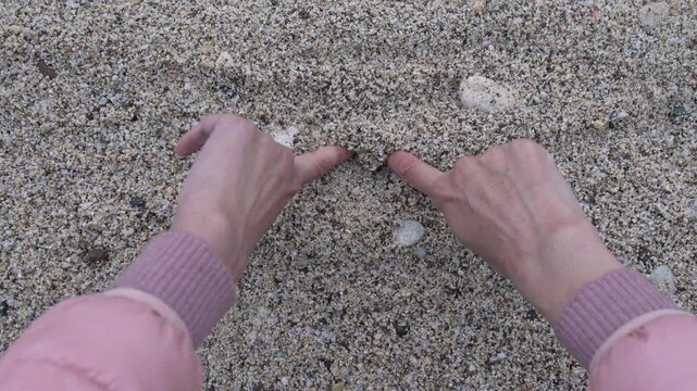 Heart sand hands drawing romantic shape on the beach in close up point of view expressing love and affection