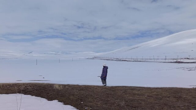 Footage of a woman walking through a minimal landscape with endless white ground and deep blue sky, creating a clean and surreal visual scene.