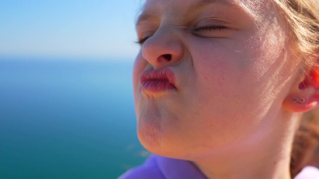 Child expression outdoors making funny pouting faces by the sea before putting on stylish sunglasses for a playful summer moment