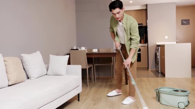 Young man guy washing floor use mop cleaning apartment, household housekeeping in positive mood, domestic work, householding, man mopping cleans house, housework and gadgets concept.