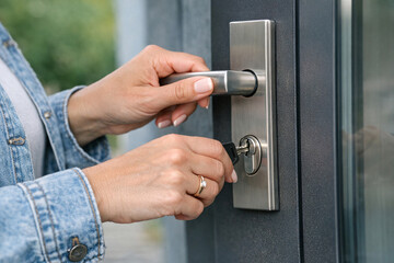 Naklejka premium A person with a denim jacket is opening the door with a key.