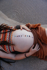 Maternity image of a mother with relaxing stones on her belly near water.  © belyaaa