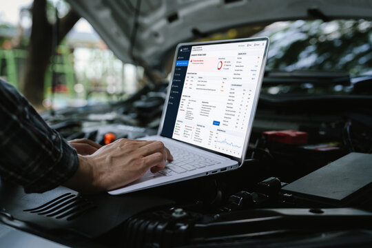 Technician using a laptop to diagnose engine performance under an open hood, analyzing vehicle data and troubleshooting automotive issues with digital diagnostic software.