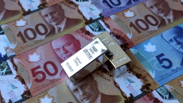 A silver bar, white metal against a backdrop of Canadian money, as a concept for the sales market. A silver bar as a background for your design