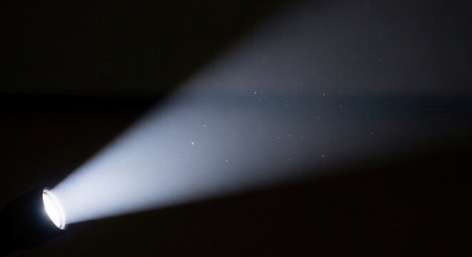 A bright beam of white light cutting through total darkness.