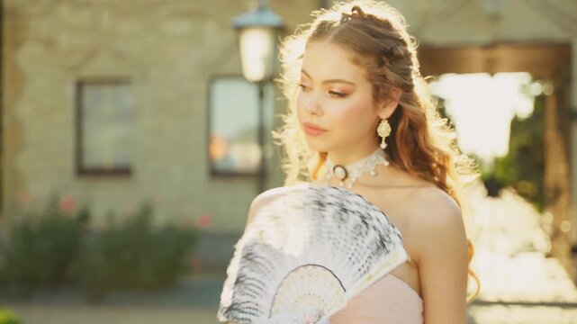 Portrait beauty face vintage lady happy smiling girl princess holding fan in hands waving wind hail fly. green garden. Young fantasy woman queen back rear view pink dress white long gloves old style