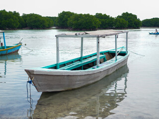 Obraz premium Traditional island boat floating quietly near the shore, surrounded by calm turquoise water and sandy beaches