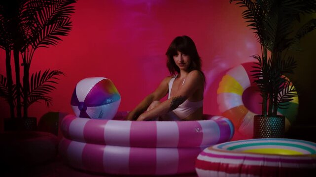 Woman Sitting in Inflatable Pool Float Under Pink Lighting