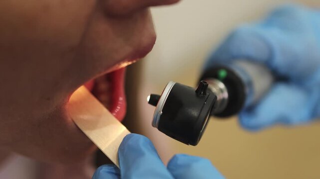 Doctor's appointment. Otoscope. Flashlight. Mouth. Tongue depressor. Slow motion video. High quality 4k footage