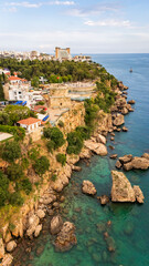 Obraz premium High angle drone view of the historic Hidirilik Tower standing on steep rocky cliffs along the Mediterranean coast of Antalya old town Kaleici, scenic maritime landscape, Turkey