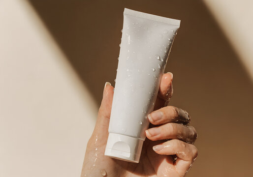 Minimalist white skincare tube mockup held in hand under warm natural light.