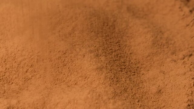 Close up of aromatic cacao powder pouring onto a pile in slow motion.