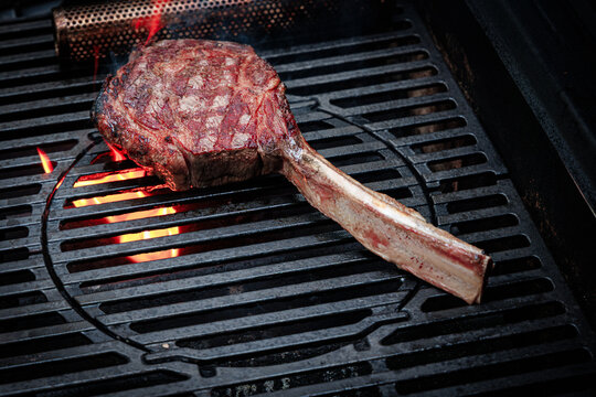 Steak grilling on an outdoor barbecue during evening hours near a home