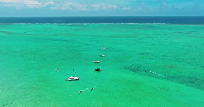 Aerial view of boats and catamarans with tourists and a passing kitesurfing near the famous Crystal Rock landmark with crystal clear turquoise water in the lagoon on Mauritius Island, Indian Ocean
