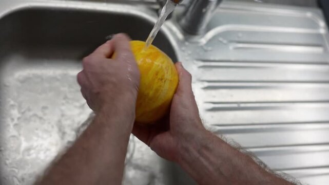 Man Washing Yellow Melon Under Running Water In Kitchen Sink Before Cooking Meal Full HD Video