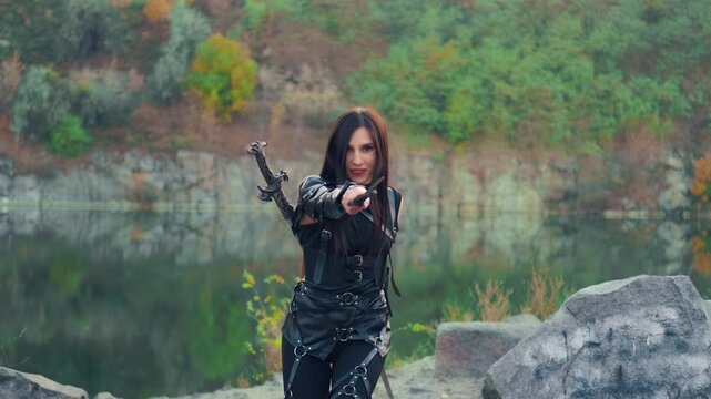 Portrait fantasy woman warrior assassin holding two burning flame fire blade daggers in hands. hiding face mask. Armed warlike girl. Black leather costume ninja soldier. sexy fashion model posing 4k 