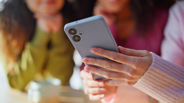 Emotional girls watching mobile phones reading messages together home closeup.