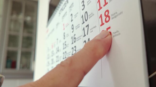Senior Woman Checking the Dates in the Kitchen Calendar 