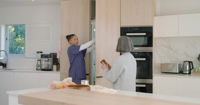 Female Senior Asian  and  African American caregiver opening cabinet handing gold jar organizing pan