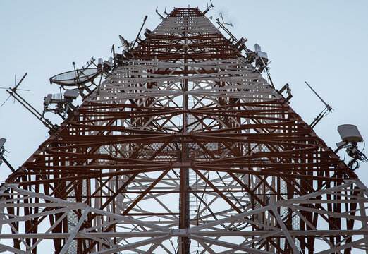 ow angle view of telecommunication tower with antennas against overcast sky.