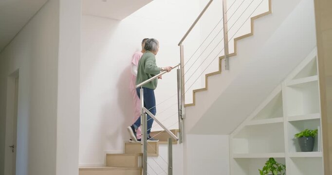 Entering home stairs, diverse senior woman and carer in scrubs climbing, using handrail for safety