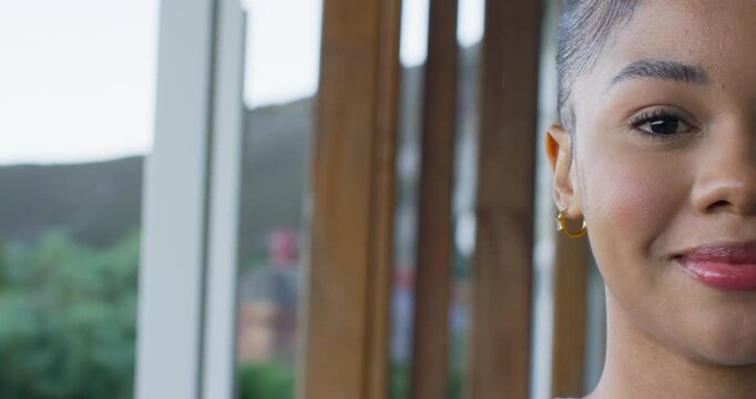 Adult African American woman blinking then laughing on balcony wearing hoop earrings, copy space