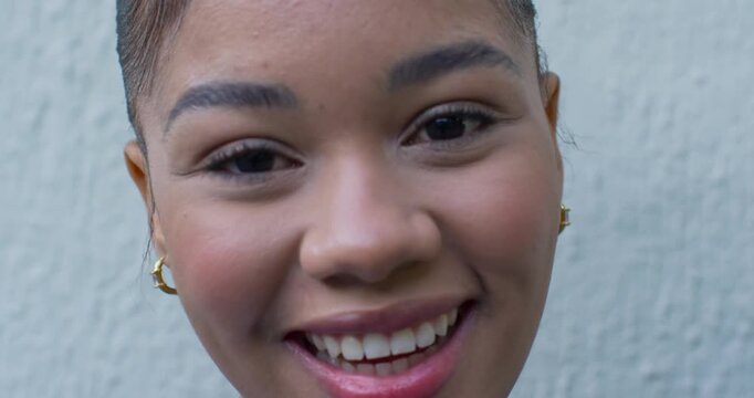 Adult African American woman on camera closeup talking laughing gold hoops lipstick textured wall