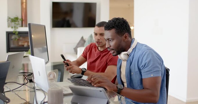 African American coworkers at glass desk in blue red typing tapping phone moving laptop fixing bug
