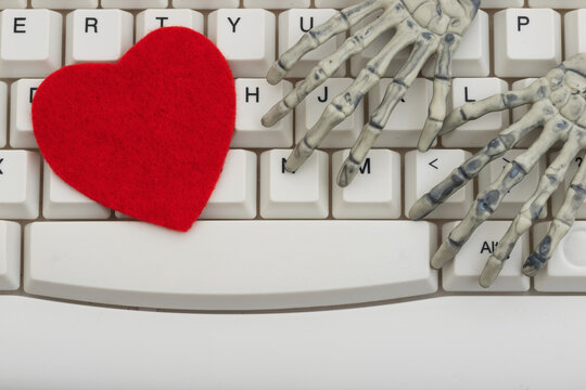 Blank red heart with a skeleton hand white computer keyboard for online romance scams