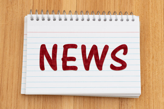 News text on a spiral notebook of index cards on wood desk