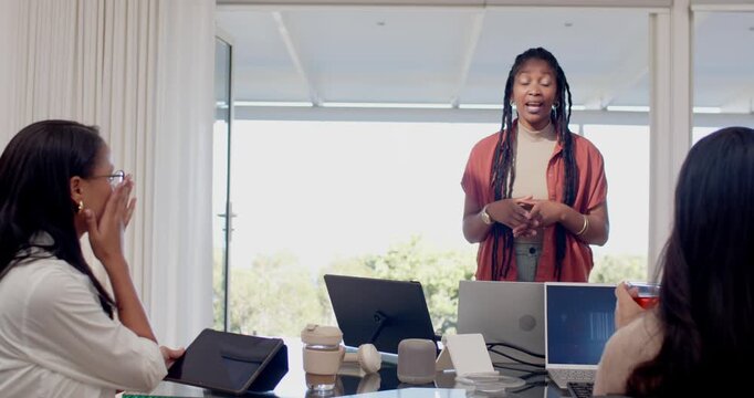 Diverse female coworkers watching presenter following plan and gesturing at glass table with laptop