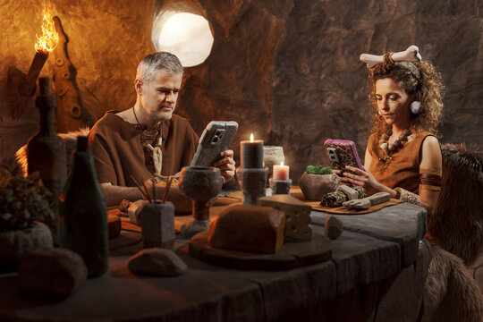 Prehistoric Couple Using Stone Smartphones at Dinner &ndash; Concept of Social Isolation and Digital Addiction