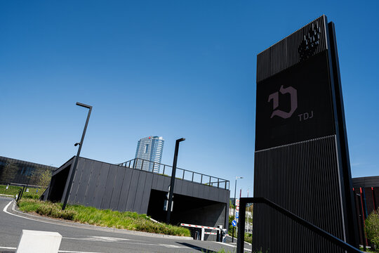 Modern commercial tower and entrance with digital signage and ramp in Katowice, Poland under a clear blue sky