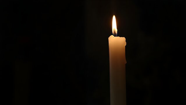 A single white candle burning in a dark chapel with warm glow and wax drips.