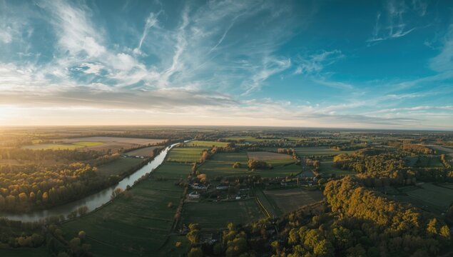 Aerial panorama of rural landscape with farmland, river, hills, and atmospheric godrays
