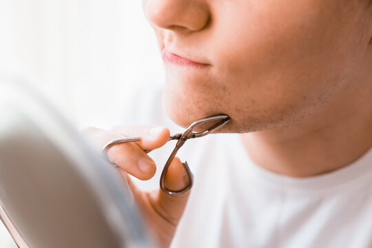A woman looks in a mirror, using tweezers for facial hair removal on her chin to manage unwanted hair and hormonal changes in her daily home beauty routine.