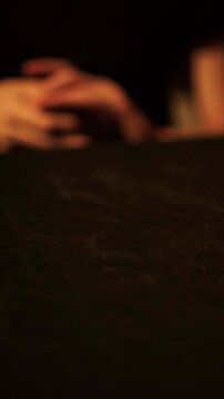 Hands slightly lifting playing cards to look at hand during dramatic card game and lowering them back over dark table, gambling and betting atmosphere, strategy and money risk concept.