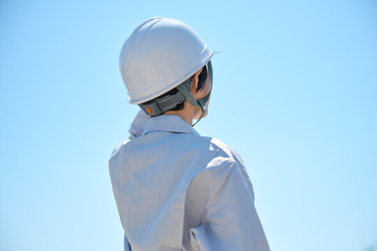 空を見上げる女性作業員の後ろ姿