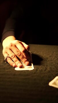 Hand of bearded man slightly lifting playing cards to check hand during emotional card game and lowering them back onto dark table, gambling and betting atmosphere, strategy and competition concept.